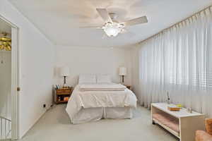 Bedroom with ceiling fan and light carpet