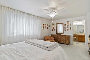 Carpeted bedroom with ceiling fan and ensuite bathroom