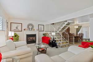 Carpeted living room featuring ornamental molding, a healthy amount of sunlight, and a notable chandelier