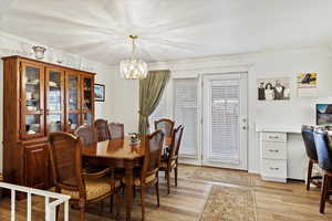 Dining room featuring crown molding, an inviting chandelier, and light hardwood / wood-style floors