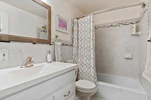 Full bathroom with tile walls, vanity, toilet, and shower / bath combo