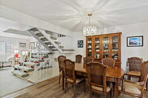 Dining room with ornamental molding, hardwood / wood-style floors, and an inviting chandelier