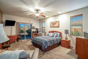 Carpeted bedroom with access to outside, stainless steel fridge, and ceiling fan