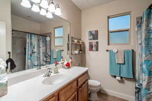 Bathroom featuring curtained shower, a chandelier, tile patterned flooring, vanity, and toilet