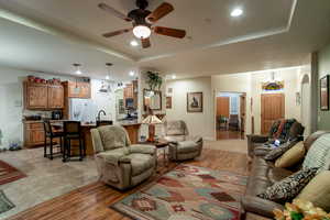 Living room featuring light hardwood / wood-style floors, a raised ceiling, and ceiling fan