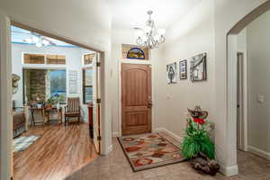 Tiled foyer with ceiling fan with notable chandelier