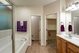 Bathroom featuring tile patterned flooring, vanity, and plus walk in shower