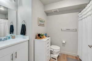 Bathroom with wood-type flooring, vanity, and toilet