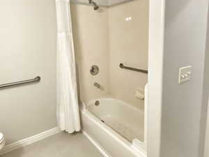 Bathroom with shower / bath combo, tile patterned floors, and toilet