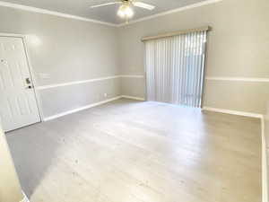 Spare room with ornamental molding, ceiling fan, and light wood-type flooring