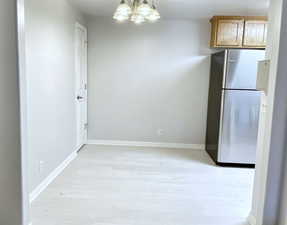 Kitchen featuring an inviting chandelier, light hardwood / wood-style flooring, and stainless steel refrigerator