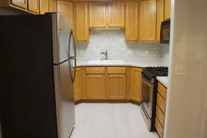 Kitchen featuring appliances with stainless steel finishes, light hardwood / wood-style floors, sink, and backsplash