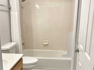 Full bathroom with vanity, shower / tub combo, and toilet