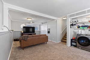 Carpeted living room featuring washer / clothes dryer, ornamental molding, and a textured ceiling