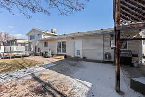 Rear view of property with central AC, a trampoline, and a patio area