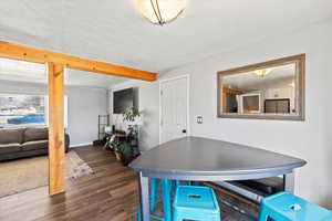 Dining space with beamed ceiling, dark hardwood / wood-style flooring, and a textured ceiling