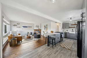 Kitchen featuring a breakfast bar area, stainless steel gas range oven, a center island, light wood-type flooring, and gray cabinets