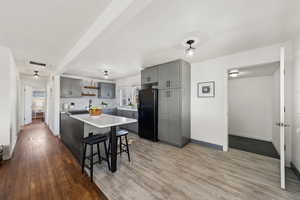 Kitchen featuring a kitchen bar, black fridge, a center island, light hardwood / wood-style floors, and backsplash