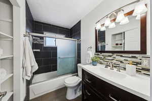 Full bathroom with tile patterned floors, toilet, tasteful backsplash, vanity, and enclosed tub / shower combo