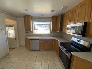 Kitchen featuring stainless steel appliances, plenty of natural light, sink, and light tile patterned floors