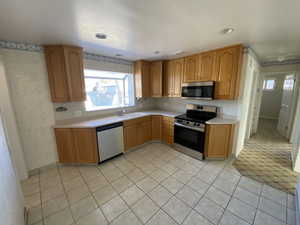 Kitchen featuring stainless steel appliances, sink, and light tile patterned floors