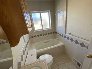 Bathroom featuring toilet, tile patterned flooring, and tile walls