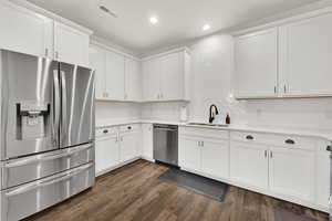 Kitchen with white cabinetry, stainless steel appliances, dark wood-type flooring, and sink