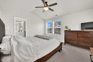 Bedroom with ensuite bathroom, lofted ceiling, light colored carpet, and ceiling fan