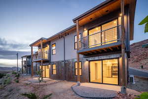 Back house at dusk featuring a balcony, a mountain view, and a patio area