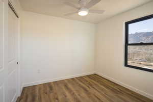 Empty room with dark wood-type flooring and ceiling fan