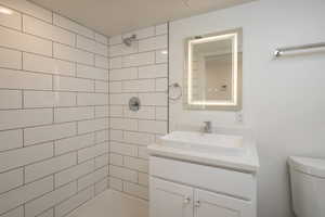 Bathroom featuring vanity, toilet, and a tile shower