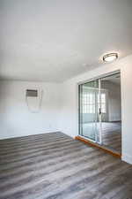 Unfurnished room featuring hardwood / wood-style floors and an AC wall unit