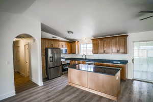 Kitchen with lofted ceiling, sink, appliances with stainless steel finishes, dark hardwood / wood-style floors, and a kitchen island