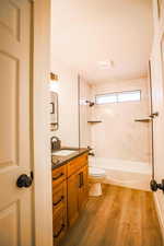 Full bathroom featuring vanity, hardwood / wood-style floors, tiled shower / bath combo, and toilet