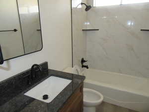 Full bathroom featuring tiled shower / bath combo, vanity, and toilet