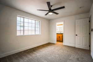 Unfurnished bedroom featuring ensuite bathroom, sink, light carpet, and ceiling fan