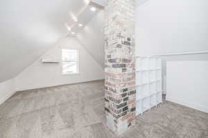 Bonus room with lofted ceiling, a wall unit AC, and carpet flooring