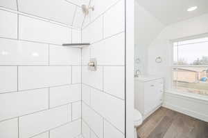 Bathroom featuring vanity, wood-type flooring, tiled shower, and toilet