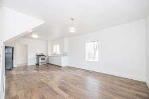 Unfurnished living room with sink, hardwood / wood-style floors, and a healthy amount of sunlight