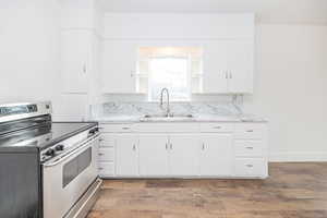 Kitchen featuring electric stove, sink, white cabinetry, and dark wood-type flooring