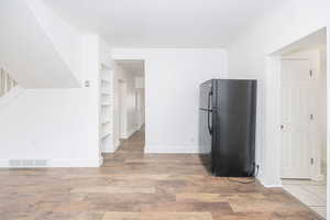 Kitchen with wood-type flooring, black refrigerator, and built in features