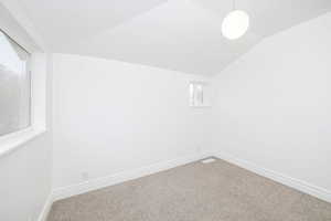 Empty room with carpet floors and vaulted ceiling