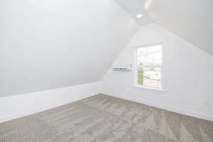 Bonus room featuring lofted ceiling, a wall mounted air conditioner, and carpet