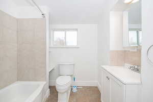 Full bathroom with vanity, plenty of natural light,  shower combination, and toilet