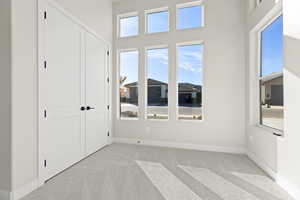 Unfurnished bedroom with light colored carpet, a closet, and a high ceiling