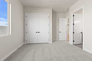 Unfurnished bedroom featuring multiple windows, a closet, and light carpet