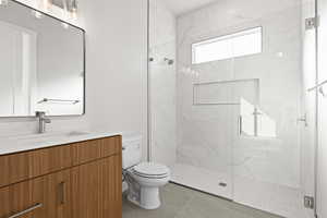 Bathroom with tile patterned floors, vanity, toilet, and a shower with door