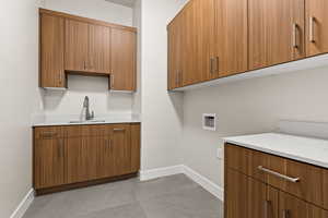 Washroom with cabinets, light tile patterned flooring, sink, and washer hookup