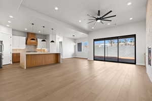 Unfurnished living room featuring ceiling fan, sink, and light wood-type flooring