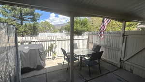 View of patio / terrace featuring outdoor dining area, a fenced backyard, a mountain view, and grilling area
